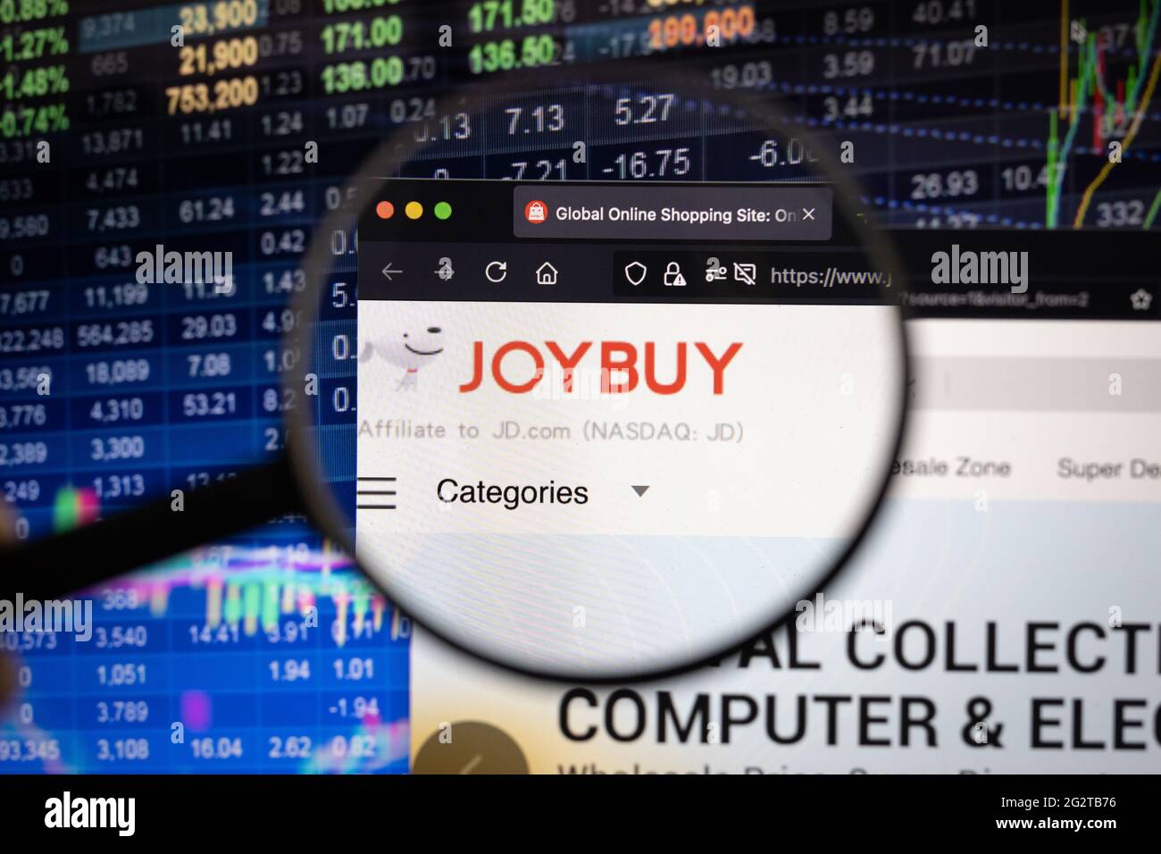 JD.com Joybuy logo aziendale su un sito web con sviluppi sfocati del mercato azionario in background, visto su uno schermo del computer attraverso una lente di ingrandimento Foto Stock