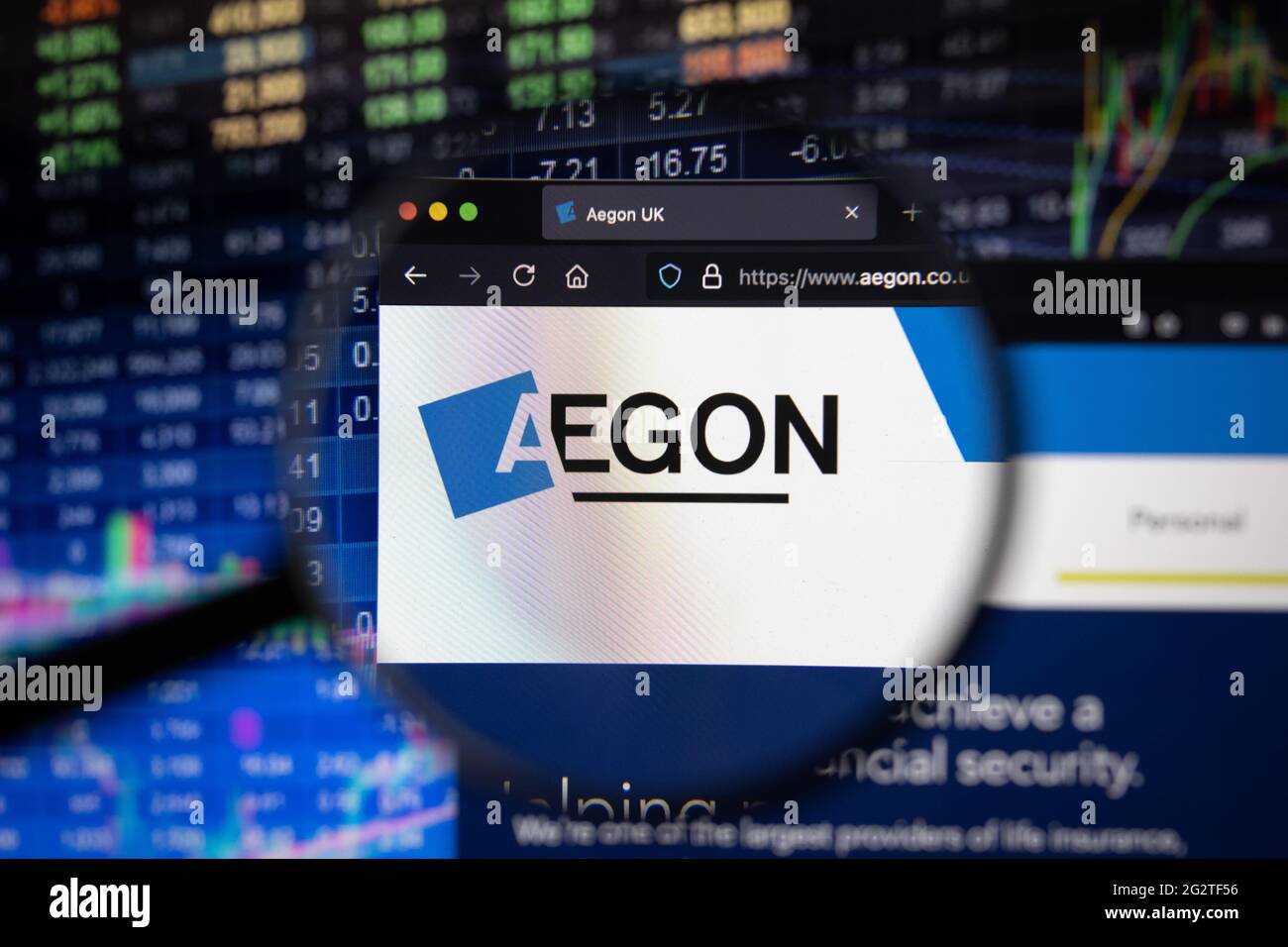 Logo aziendale Aegon su un sito Web con sviluppi sfocati del mercato azionario sullo sfondo, visto su uno schermo del computer attraverso una lente di ingrandimento Foto Stock