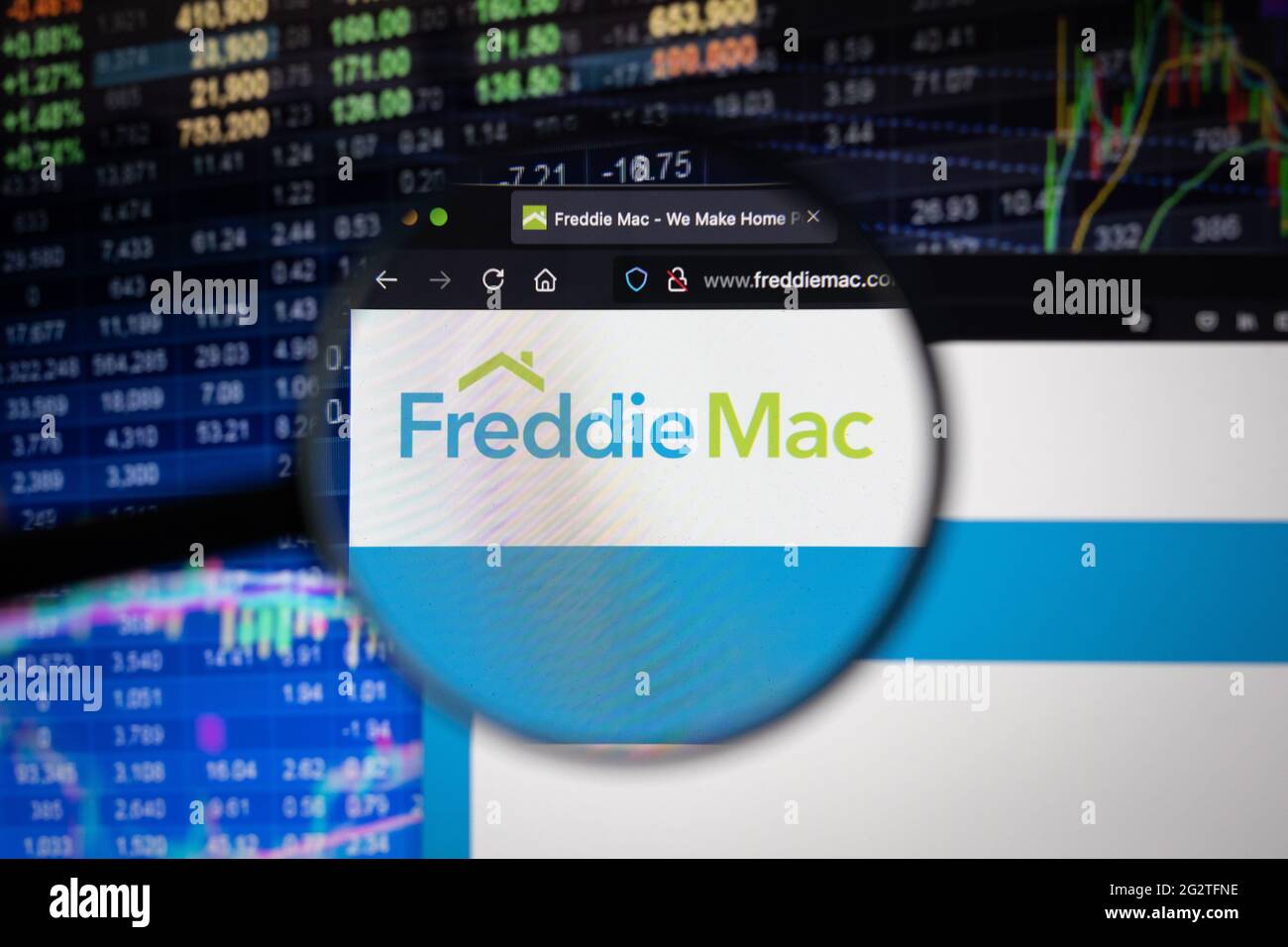 Freddie Mac Company logo su un sito web con sviluppi sfocati del mercato azionario in background, visto su uno schermo del computer attraverso una lente di ingrandimento Foto Stock