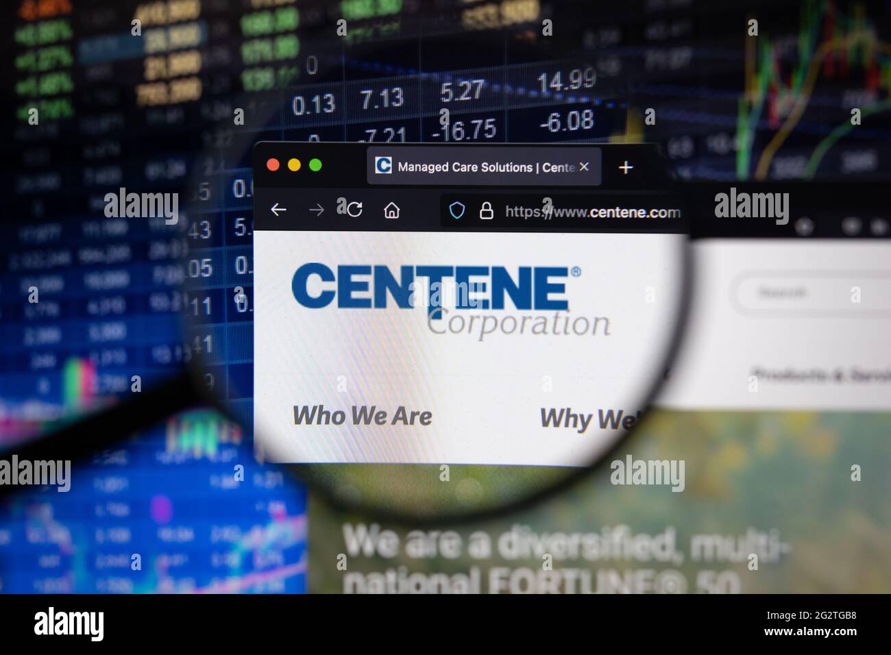Logo della società Centene su un sito web con sviluppi sfocati del mercato azionario in background, visto su uno schermo del computer attraverso una lente di ingrandimento Foto Stock
