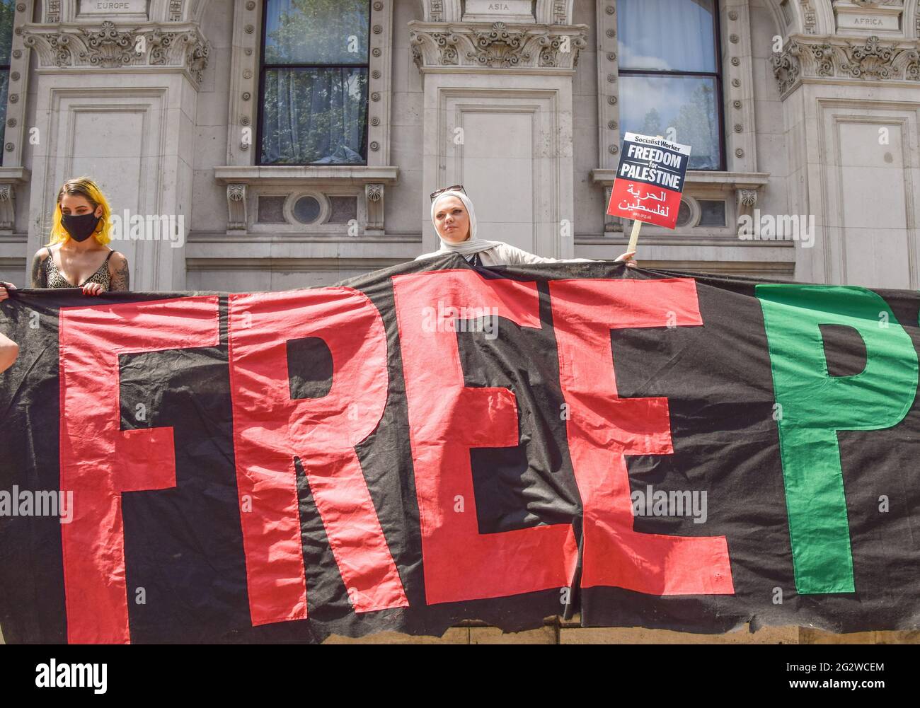 Londra, Regno Unito. 12 giugno 2021. I manifestanti tengono un cartello e cartelli fuori Downing Street durante la protesta di Justice for Palestine. Migliaia di persone hanno marciato per Londra per chiedere giustizia alla Palestina e hanno invitato il G7 a porre fine alla cooperazione militare con Israele e ad imporre sanzioni. Credit: SOPA Images Limited/Alamy Live News Foto Stock