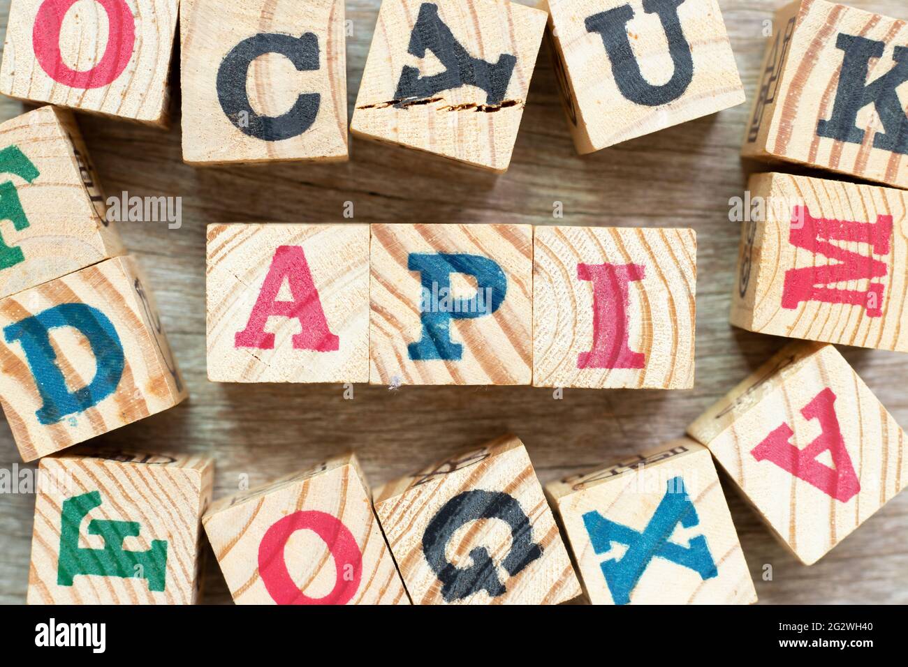 Blocco di lettere alfabetiche nella parola API (abbreviazione di Application Programming Interface o Active Pharmaceutical Ingredient) con un altro su legno backgro Foto Stock