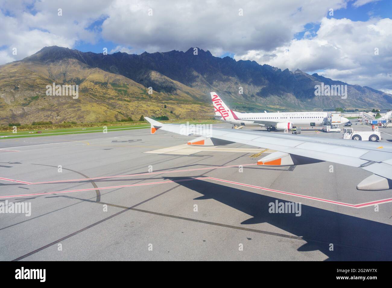 Queenstown, Nuova Zelanda - 6 marzo 2015; le montagne fanno da sfondo agli aerei parcheggiati all'aeroporto con l'ombra sotto l'ala. Foto Stock