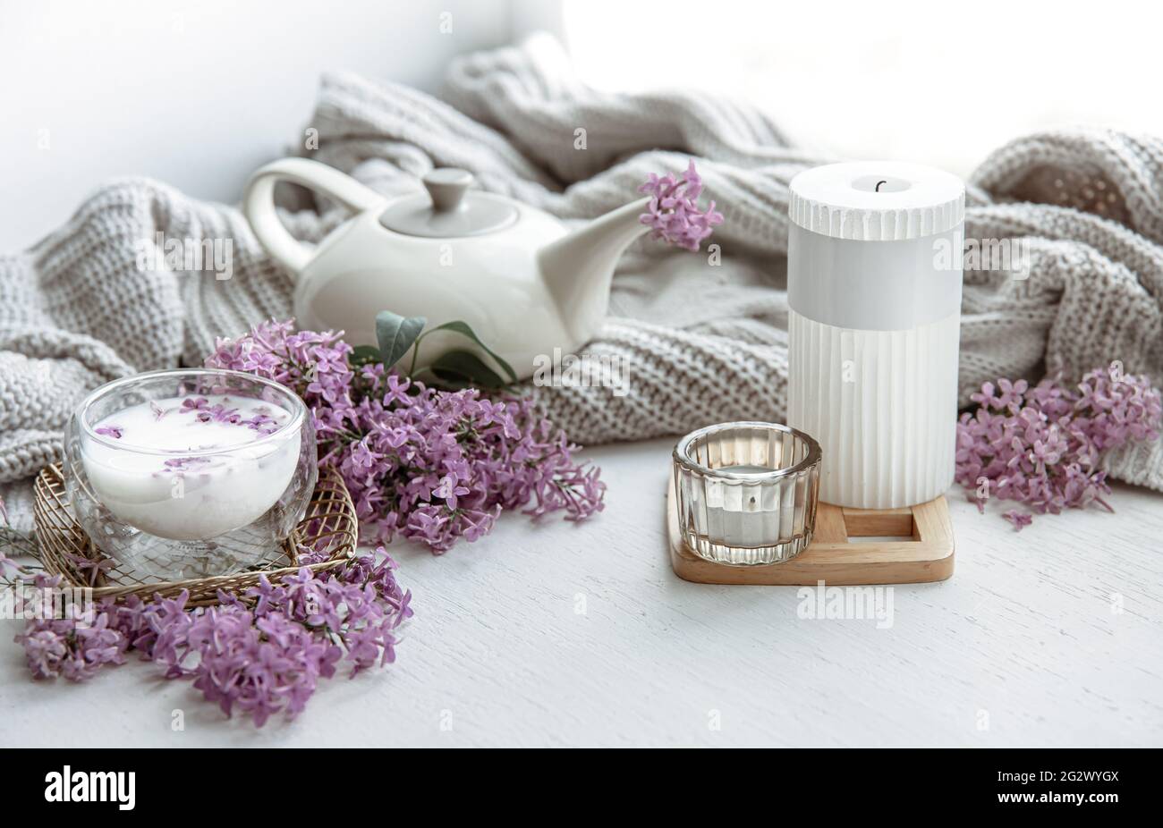Delicato arrangiamento primaverile con fiori in vaso, un bicchiere di latte e dettagli di arredamento per la casa. Foto Stock