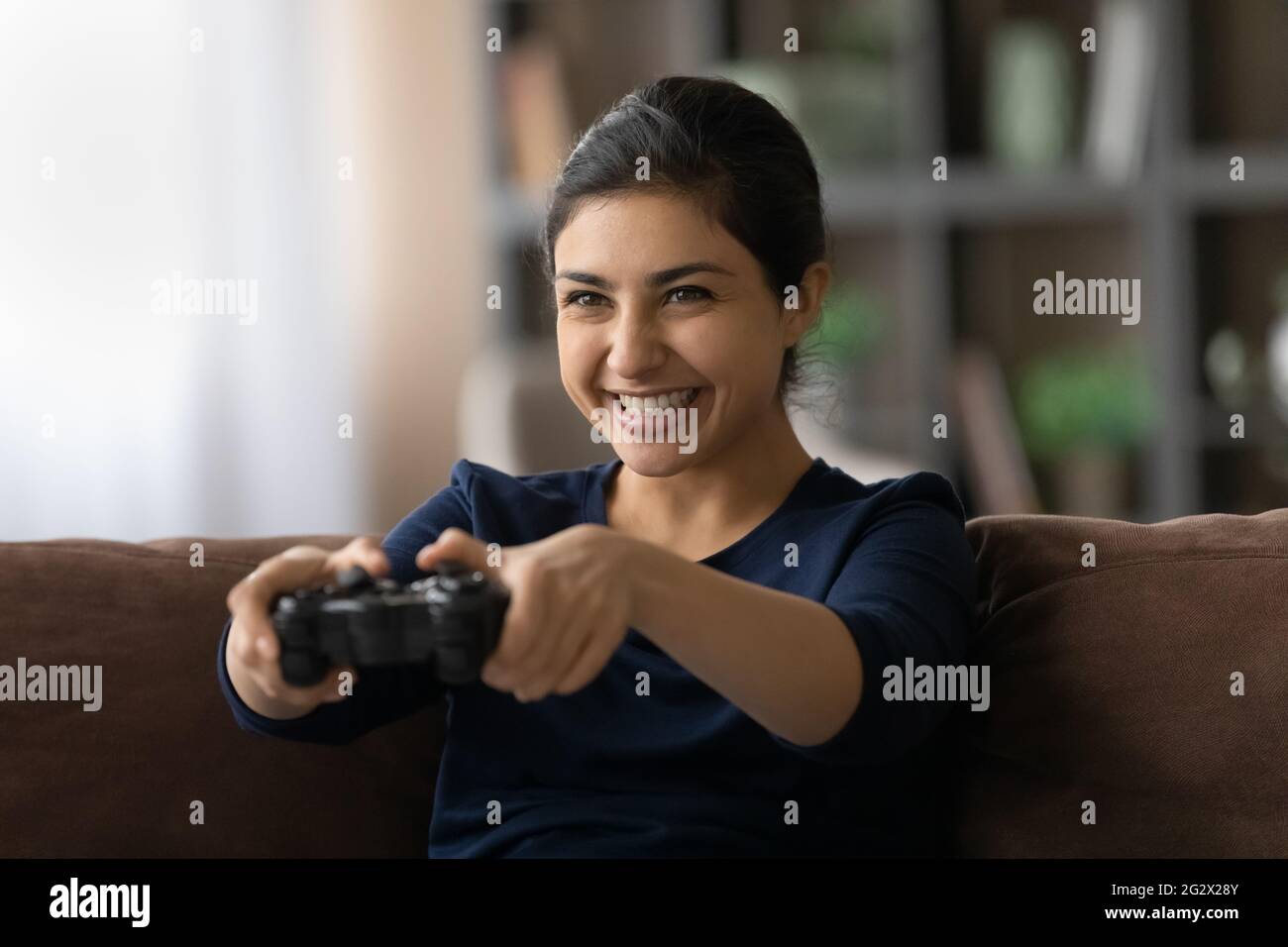 Appassionata adolescente indiana giocare il gioco di console preferito a casa Foto Stock