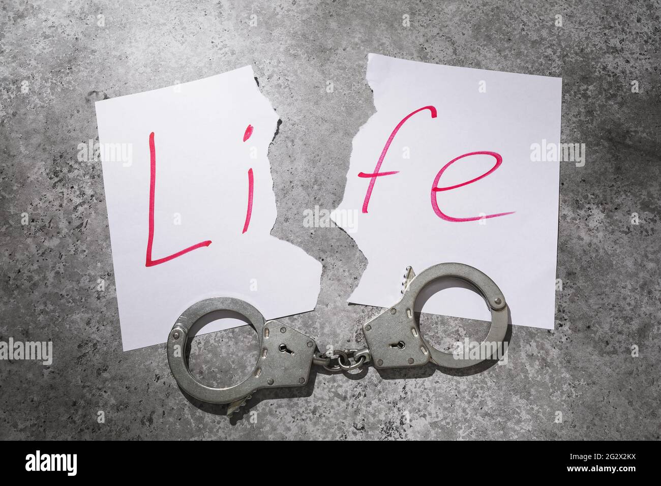 Foglio strappato con testo e manette sul tavolo, concetto sul tema di una vita viziata. Foto Stock