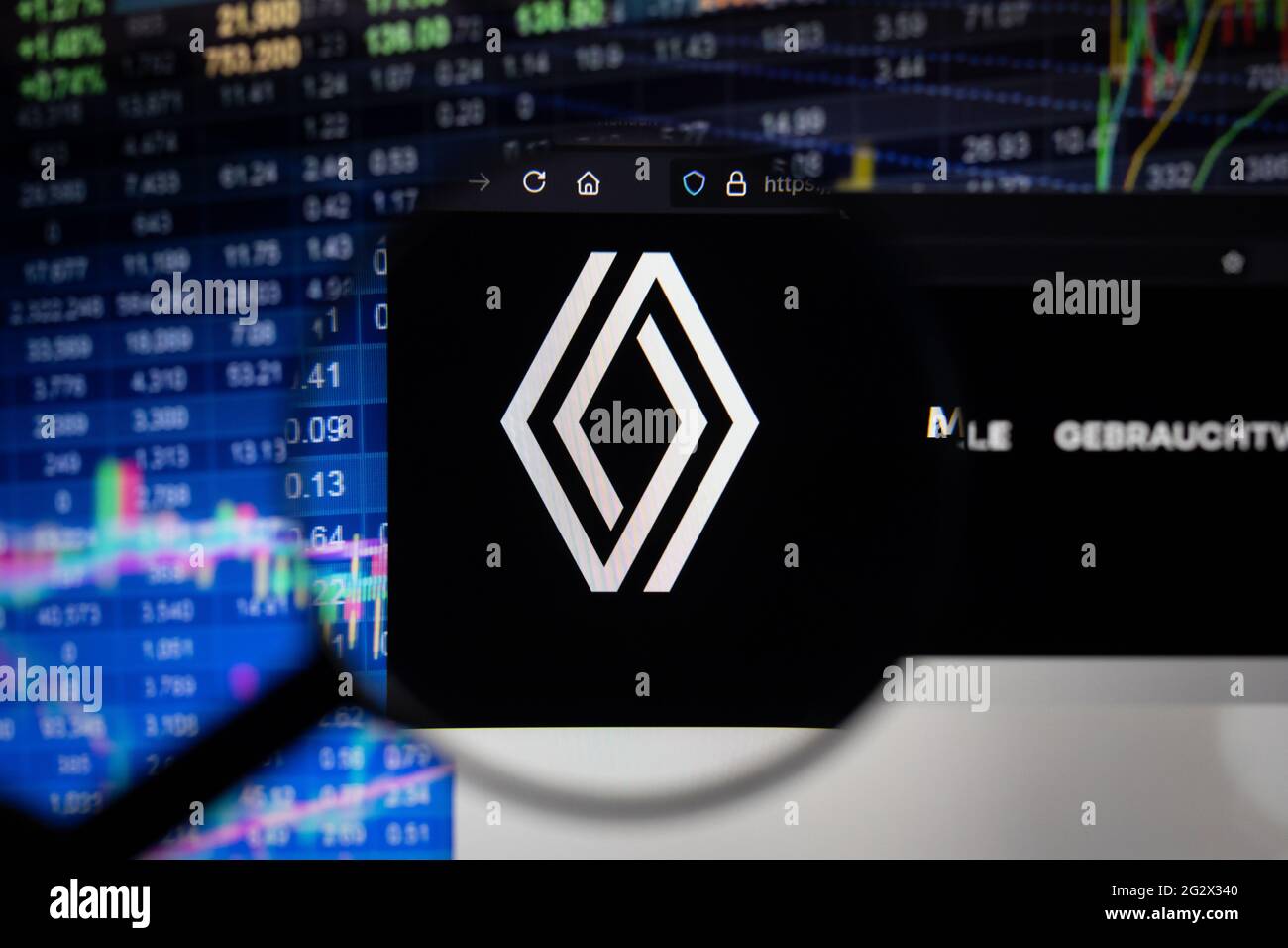 Logo della società Renault su un sito web con sviluppi sfocati del mercato azionario sullo sfondo, visto su uno schermo del computer attraverso una lente di ingrandimento Foto Stock
