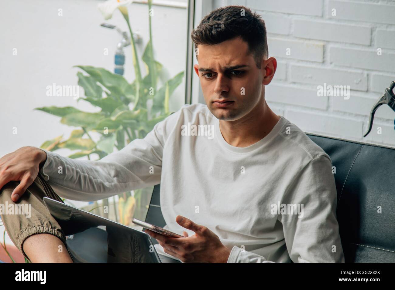 giovane premuroso con telefono cellulare a casa Foto Stock