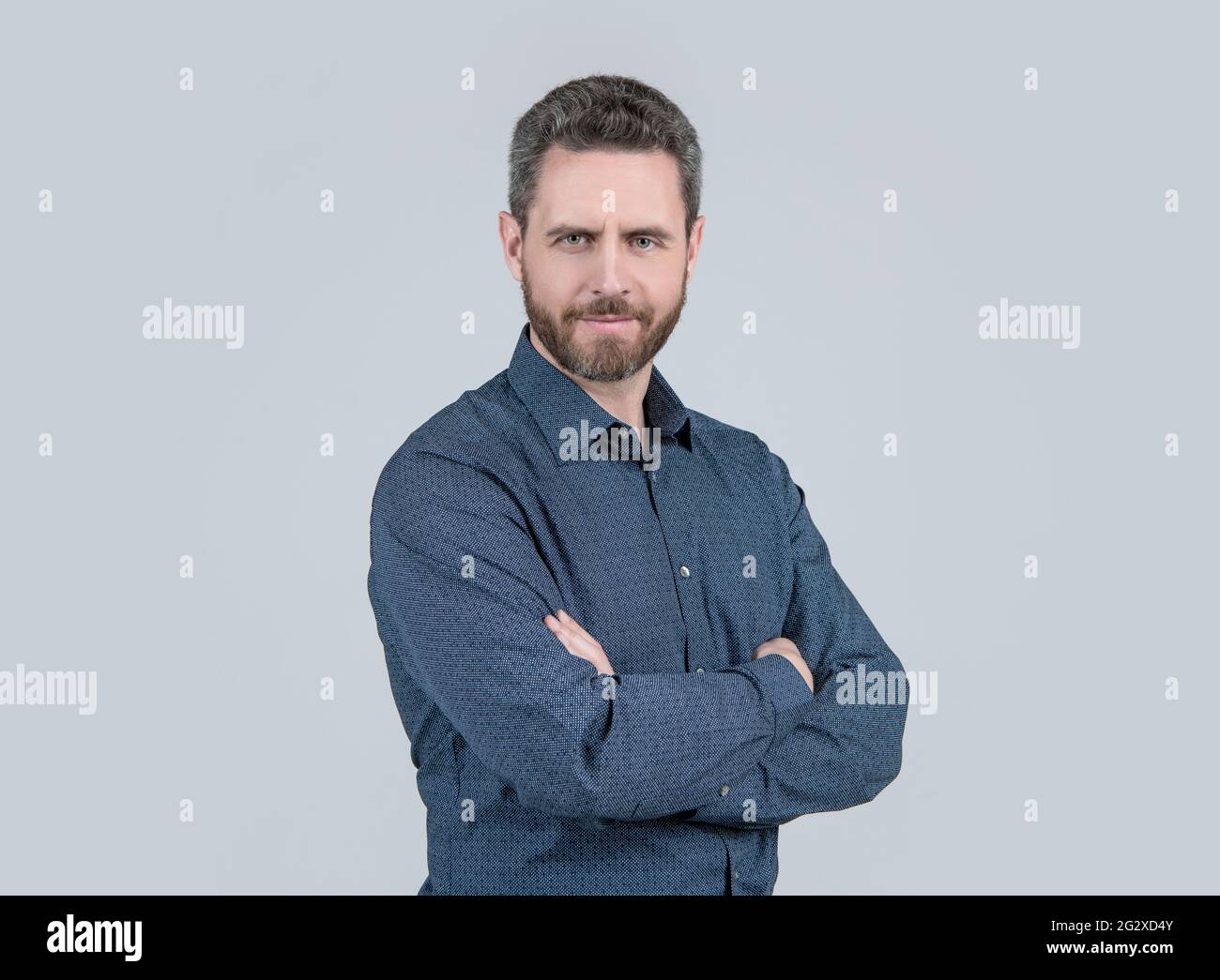 Uomo bearded in camicia casual stile mantenere le braccia incrociate sensazione di fiducia sfondo grigio, confortevole Foto Stock