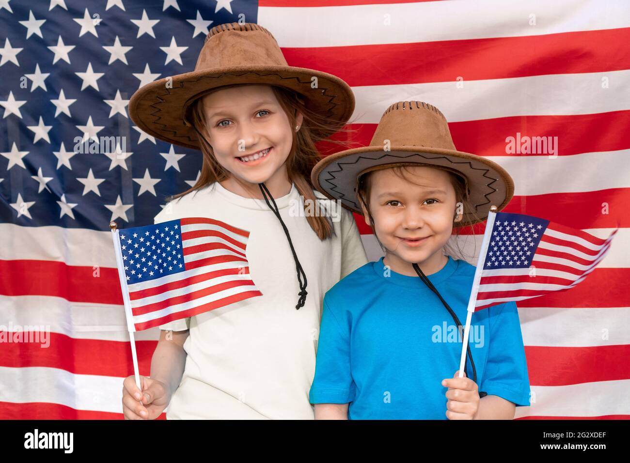 Giorno di indipendenza. Vacanza patriottica. Contenti i bambini, grazioso due ragazze con la bandiera americana. Cowboy. Stati Uniti d'America festeggia il 4 luglio Foto Stock