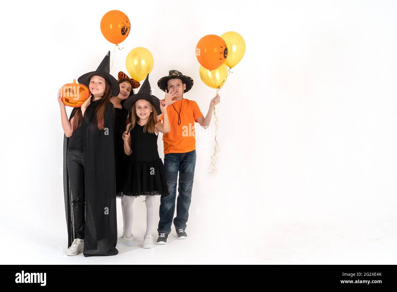 Un gruppo di bambini in costumi di Halloween sono in piedi su uno sfondo bianco e sorridente. Copia spazio. Foto Stock