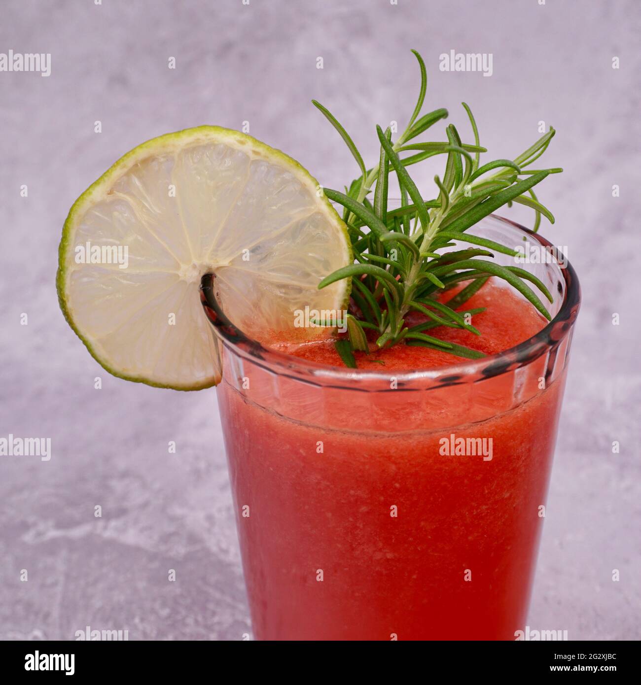 Una mocktail di frutta non alcolica in un bicchiere con contorno di limone e rosmarino Foto Stock