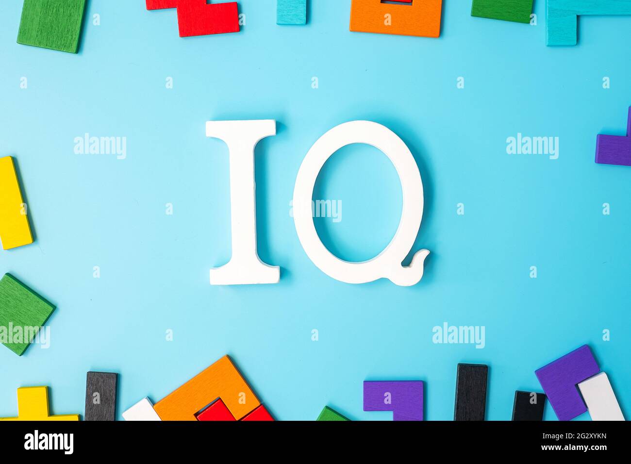 Testo IQ con pezzi di puzzle in legno colorato, blocco di forma geometrica su sfondo blu. Concetto di quoziente di intelligenza e di logica pensiero Foto Stock