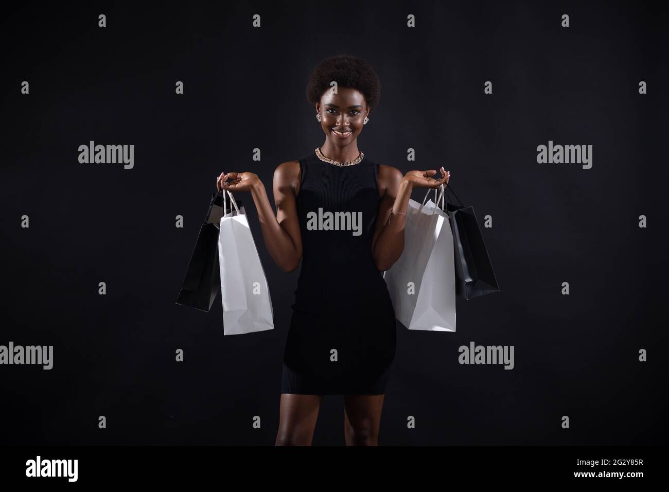 Donna afroamericana con acconciatura afro tiene borse per la spesa in bianco e nero. Vendita e sconti Black Friday Concept. Foto Stock
