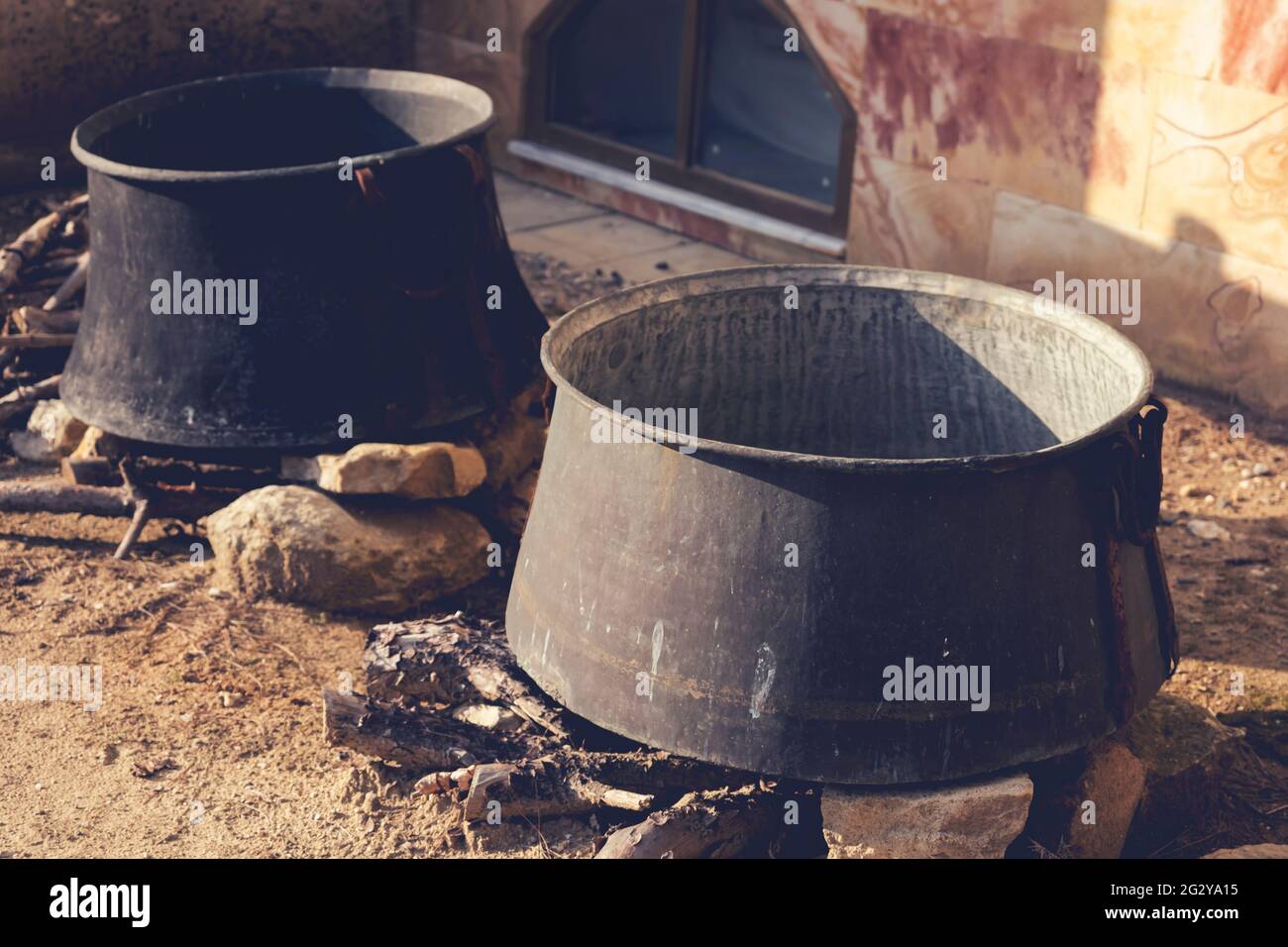 Cucinare in due vecchi cavoldri di soia sul fuoco in giornata di sole. Vista ravvicinata. Immagine con tonalità retrospettiva. Foto Stock