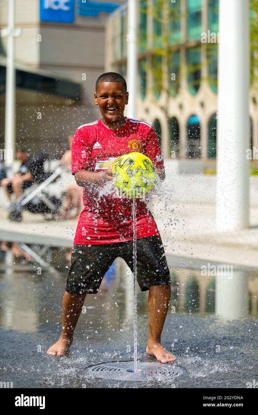 Birmingham, Regno Unito. 13 giugno 2021. Baslel, 11 anni, ha un'ora di calcio nelle fontane della piazza del Centenario di Birmingham, in quello che potrebbe essere il giorno più caldo dell'anno finora. Credit: Peter Lopeman/Alamy Live News Foto Stock