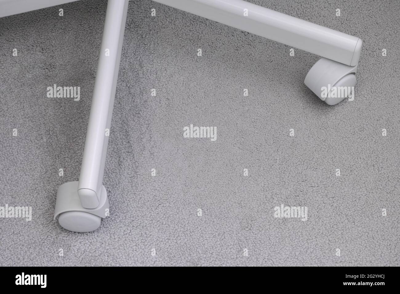 Le rotelle di una sedia da ufficio bianca. Primo piano. Foto Stock