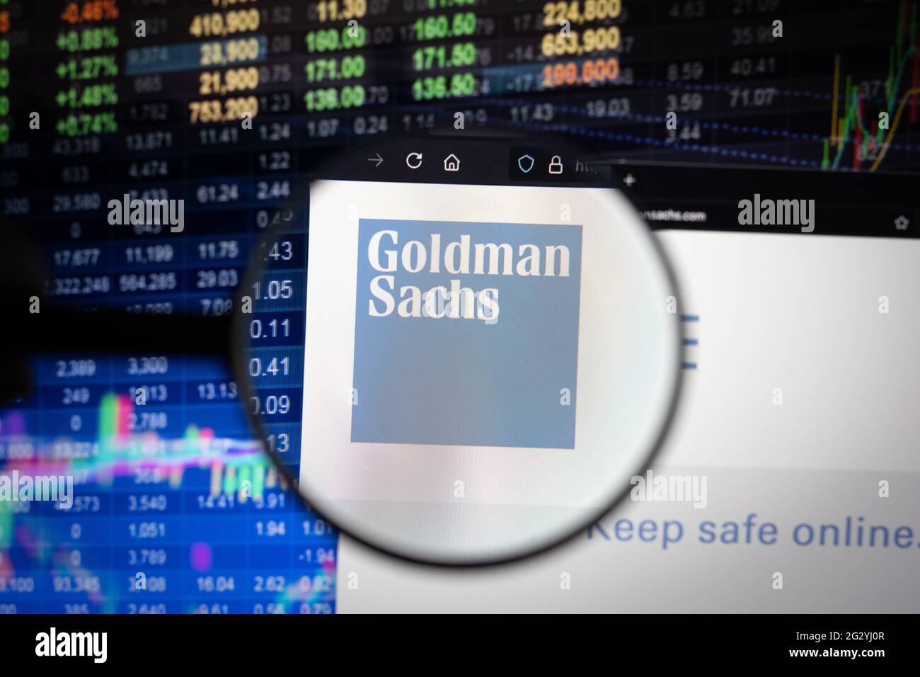 Goldman Sachs logo aziendale su un sito web con sviluppi del mercato azionario sfocato in background, visto su uno schermo del computer attraverso una lente di ingrandimento Foto Stock