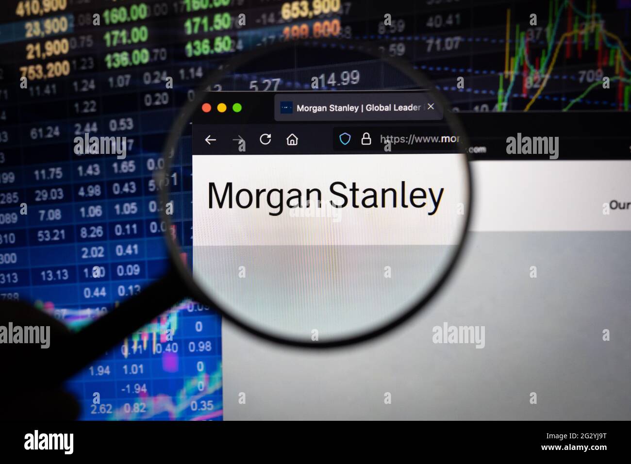 Morgan Stanley logo aziendale su un sito web con sviluppi sfocati del mercato azionario in background, visto su uno schermo del computer attraverso una lente di ingrandimento Foto Stock