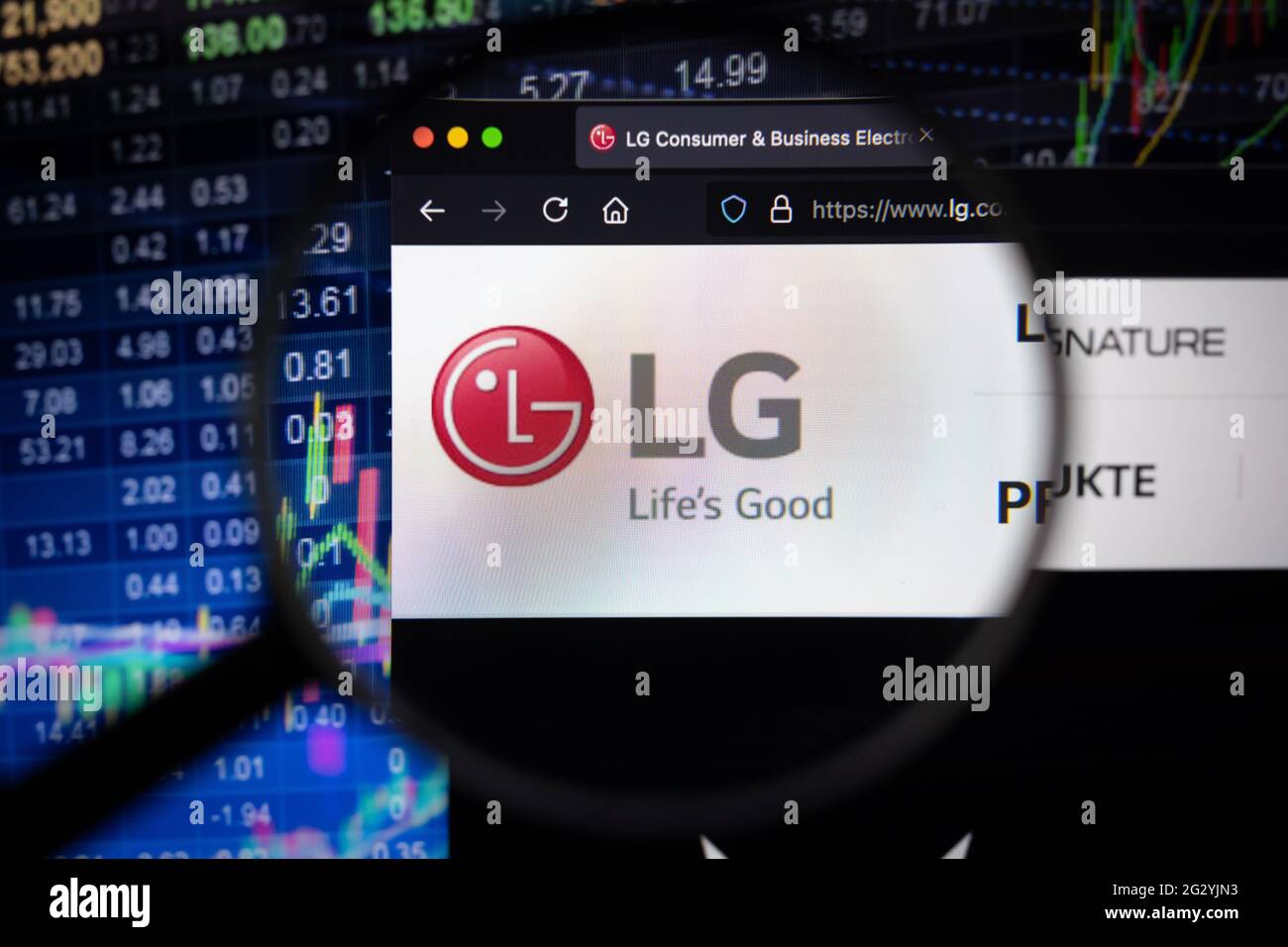 LG Electronics logo aziendale su un sito web con sviluppi del mercato azionario sfocato in background, visto su uno schermo del computer attraverso una lente di ingrandimento Foto Stock