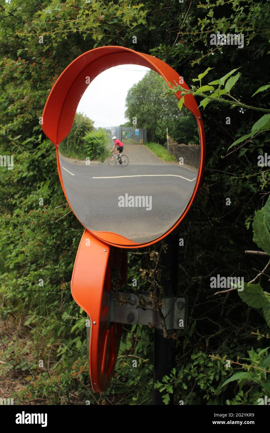 Specchio convesso per la sicurezza stradale con riflesso del ciclista sfocato con spazio di copia Foto Stock