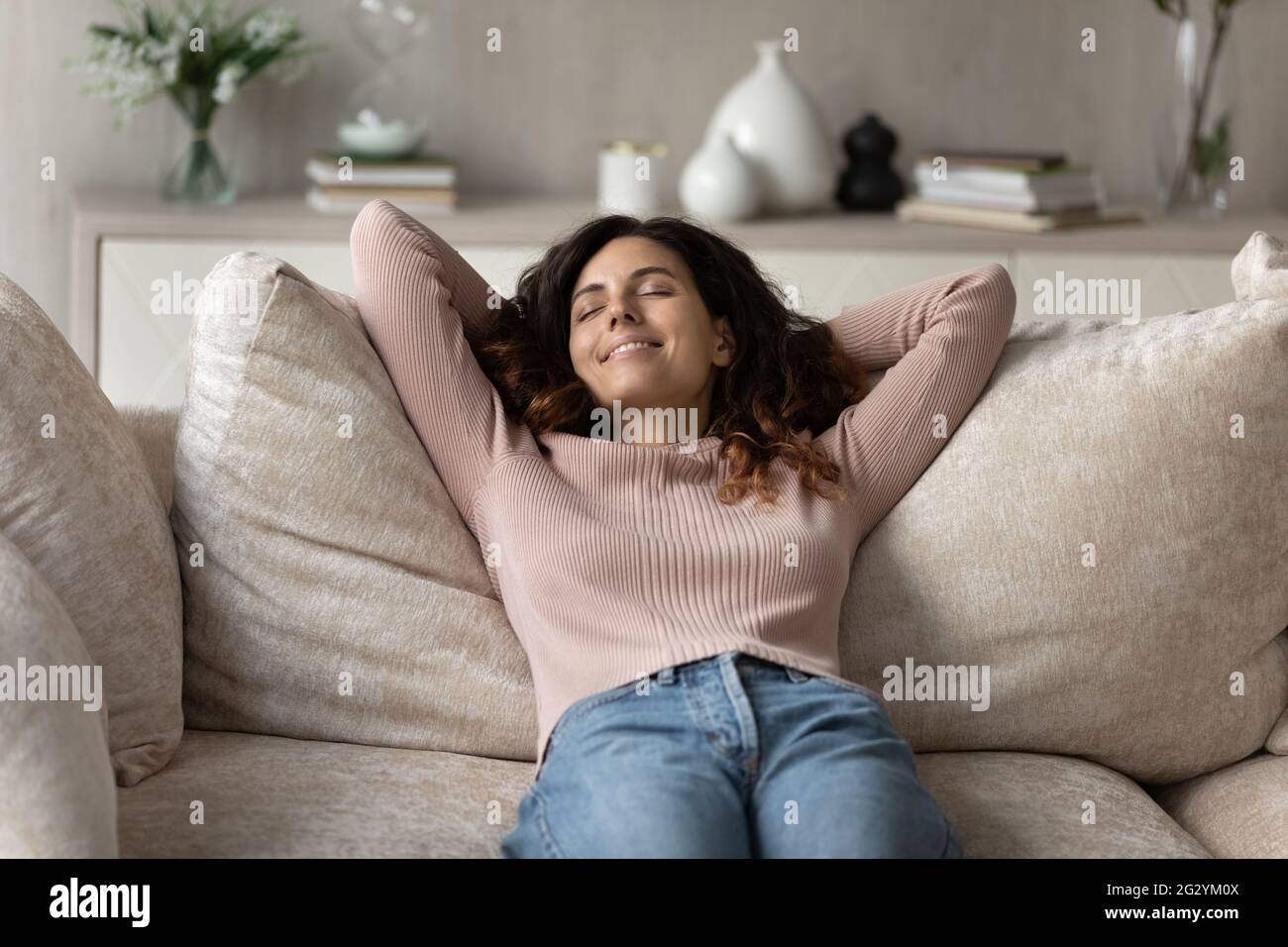 Sorridente donna ispanica rilassarsi sul divano prendendo un sonnellino Foto Stock