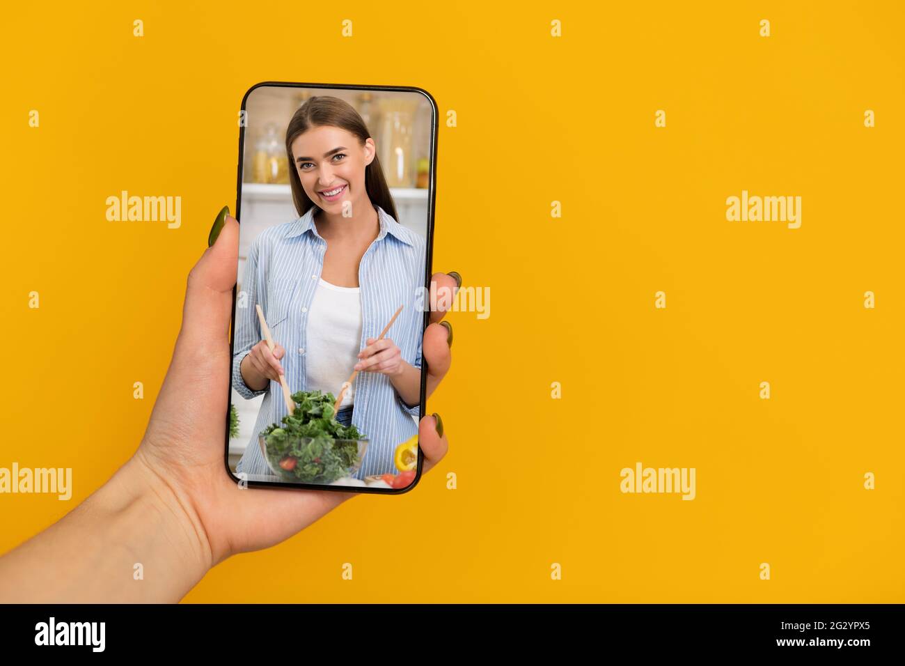 Cellulare femminile con classe culinaria online su schermo su sfondo arancione, panorama con spazio per la copia Foto Stock