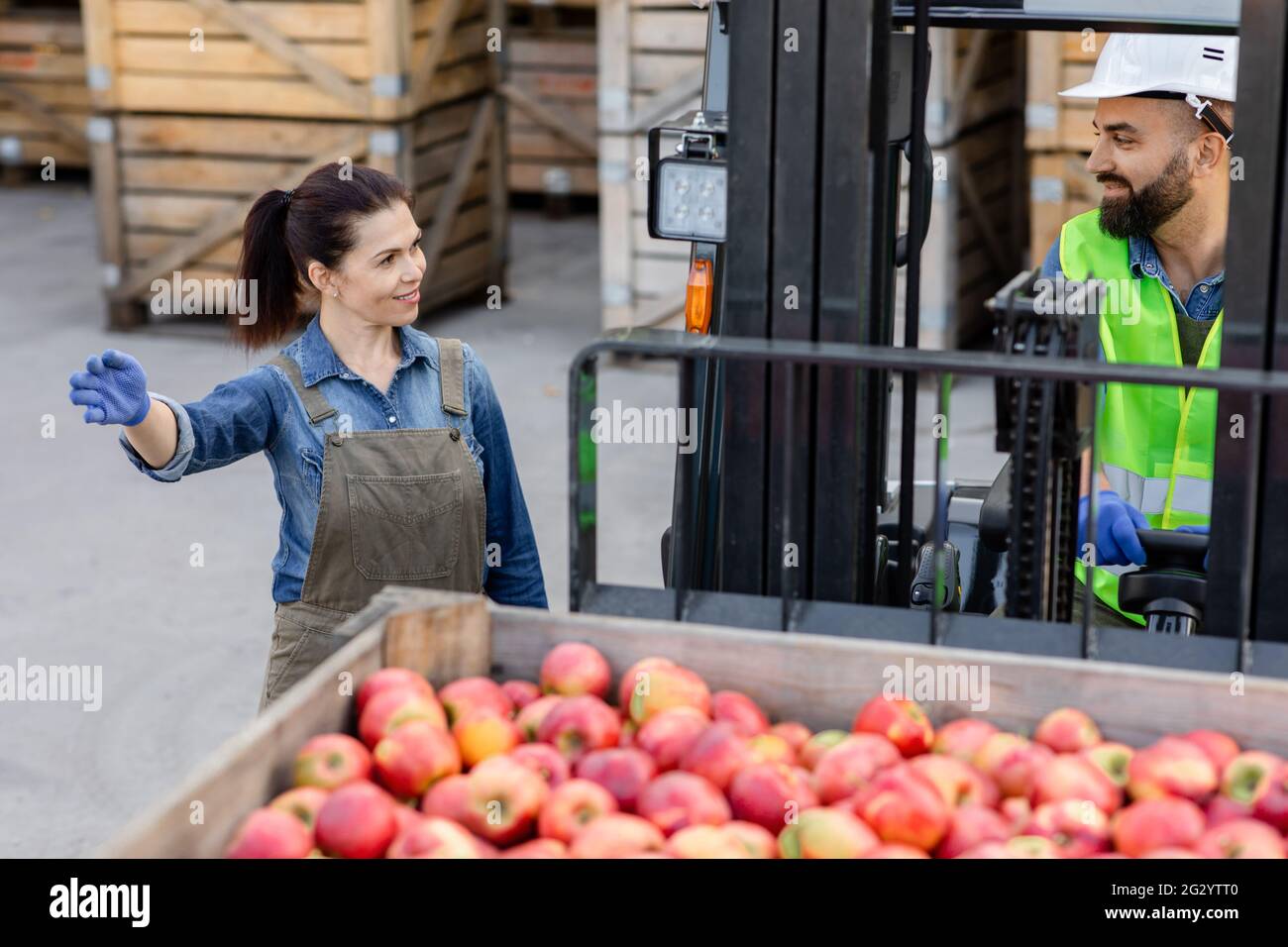 Carrello elevatore a forche con contenitore pieno di mele rosse. Frutta e distribuzione di cibo al mercato Foto Stock