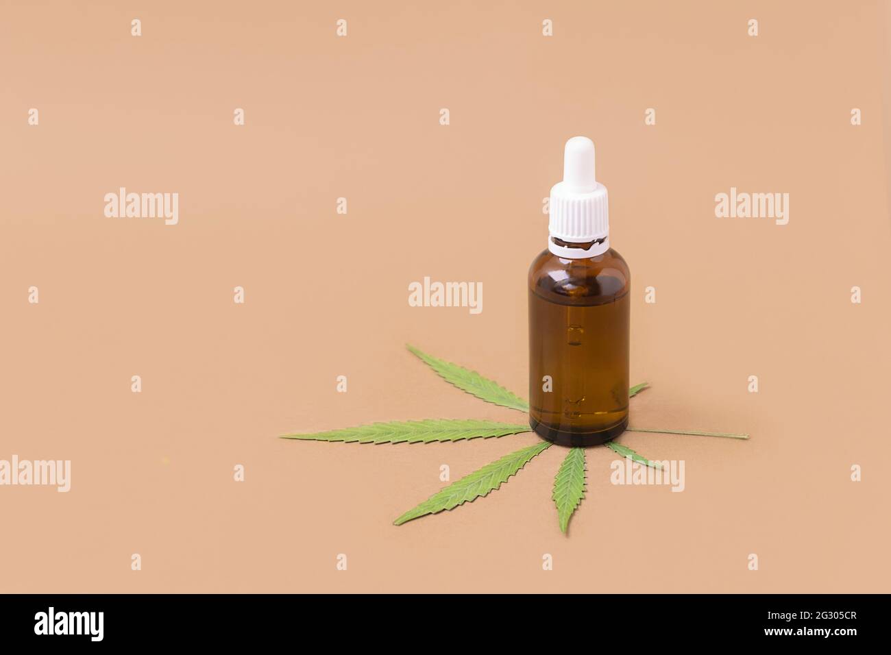 Bottiglia di olio di cannabis con foglia verde su sfondo beige con spazio per il testo. Concetto di cannabis medica Foto Stock