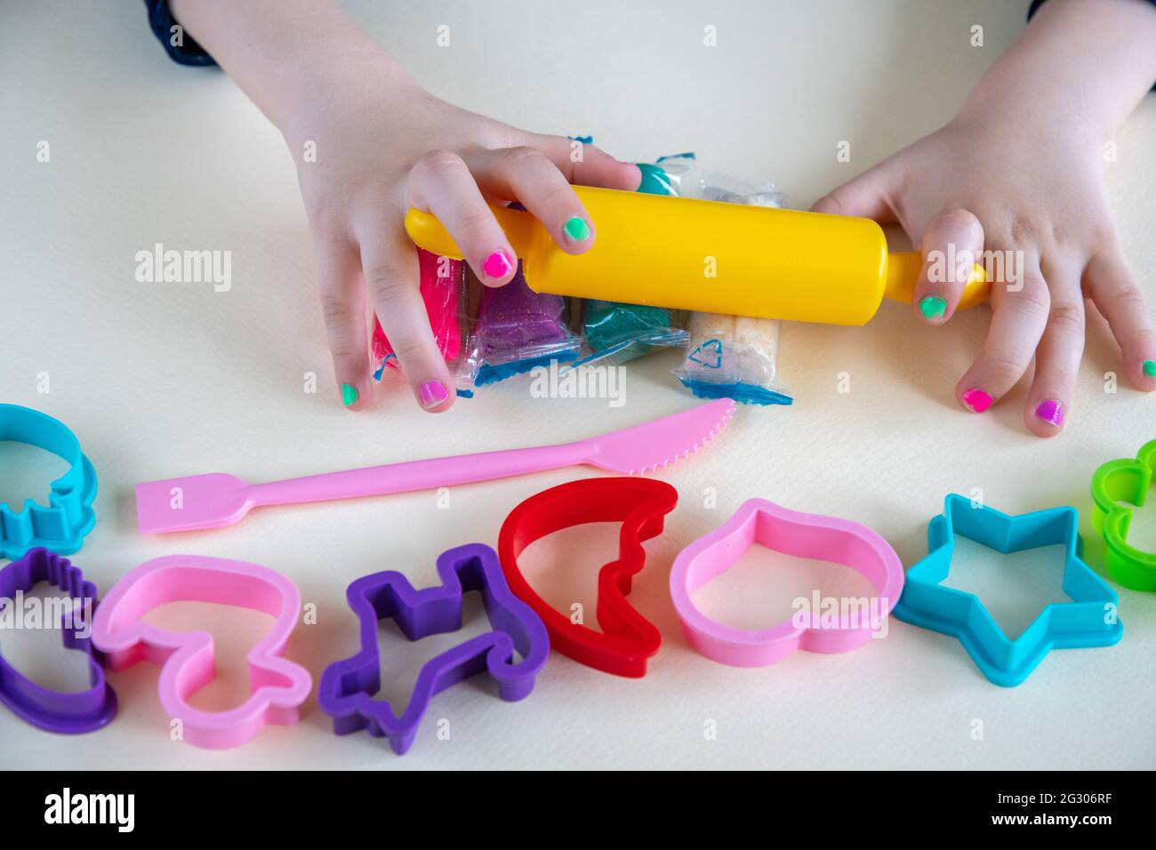 Bambina che forma e modellando plastilina o gioca a mani e con il perno di rotolamento giallo. Gioca a stampo per migliorare le capacità motorie. Ki Foto Stock