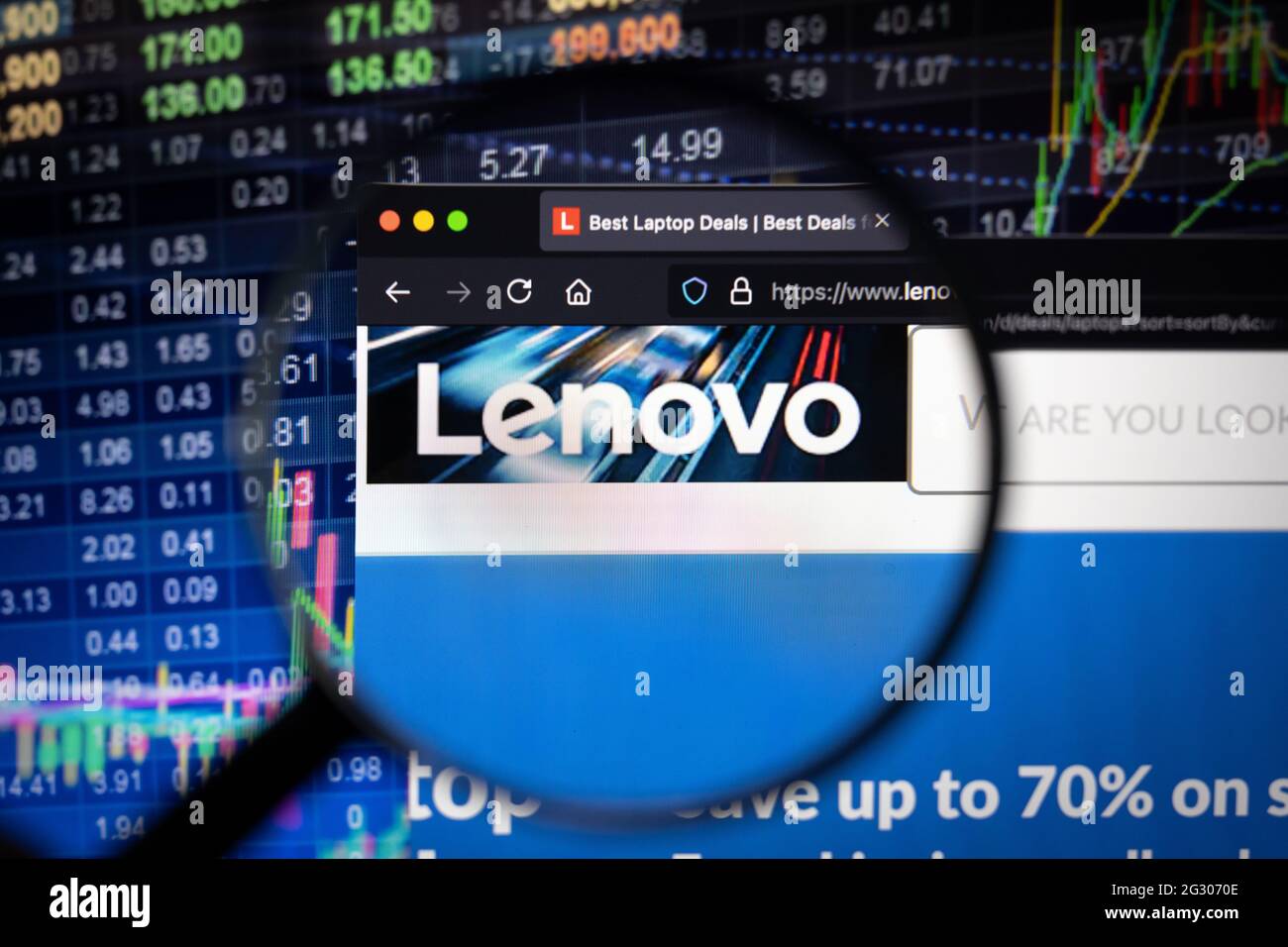 Logo aziendale Lenovo su un sito Web con sviluppi sfocati del mercato azionario sullo sfondo, visto su uno schermo del computer attraverso una lente di ingrandimento Foto Stock