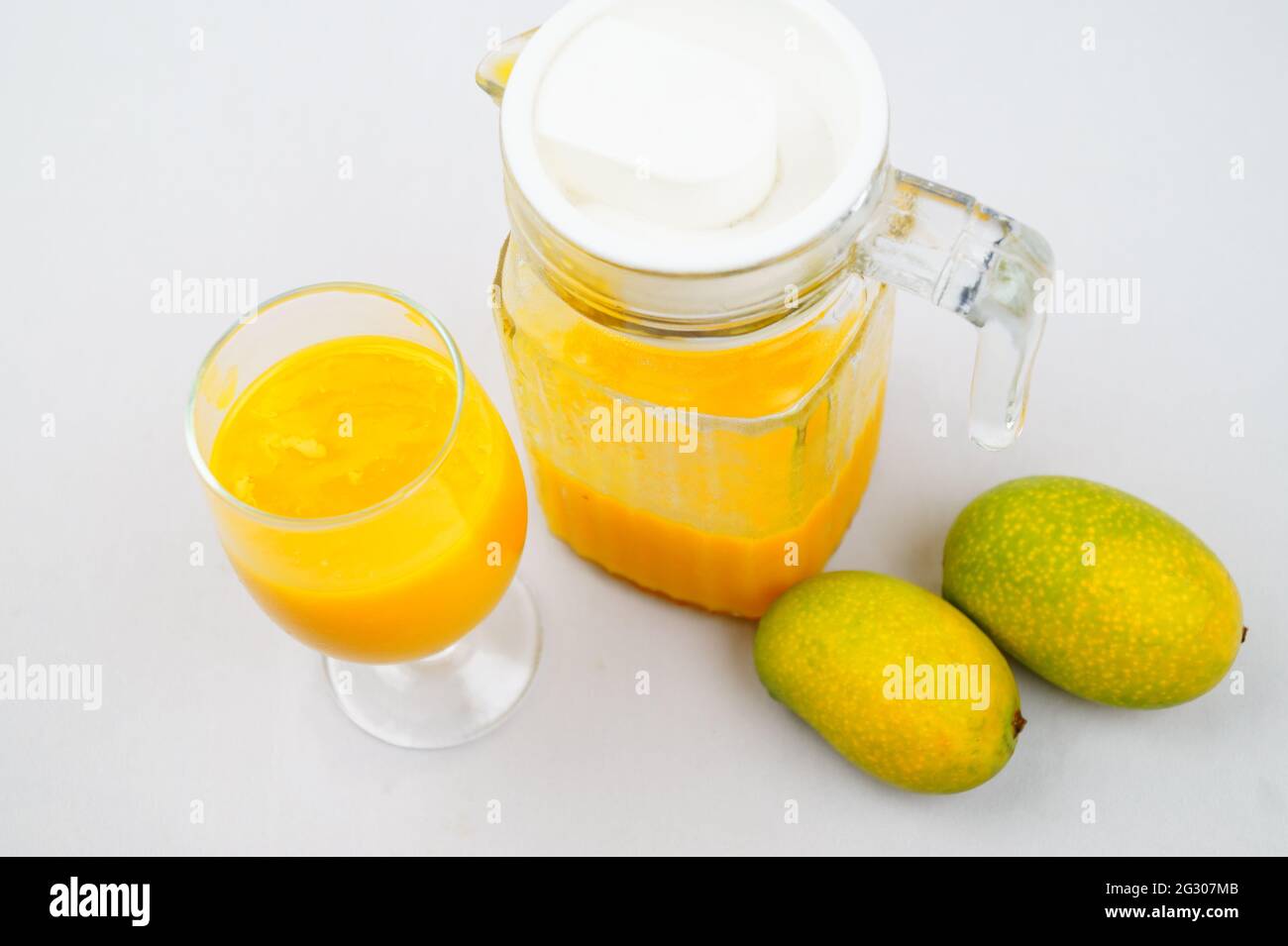 Un colpo ad alto angolo di mango, una caraffa e un bicchiere di succo di mango fresco Foto Stock