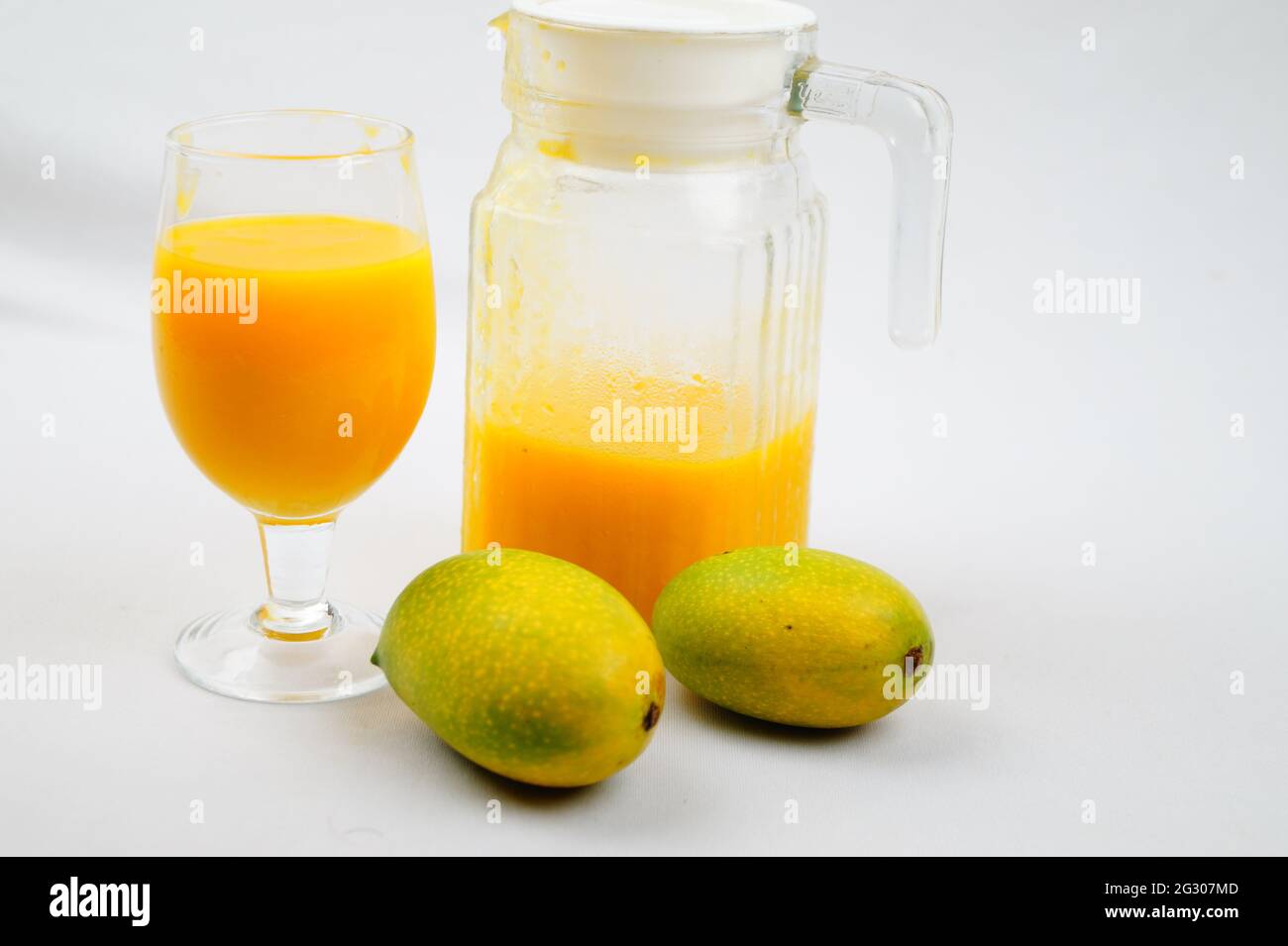 Un primo piano di mango, una caraffa e un bicchiere di succo di mango fresco Foto Stock