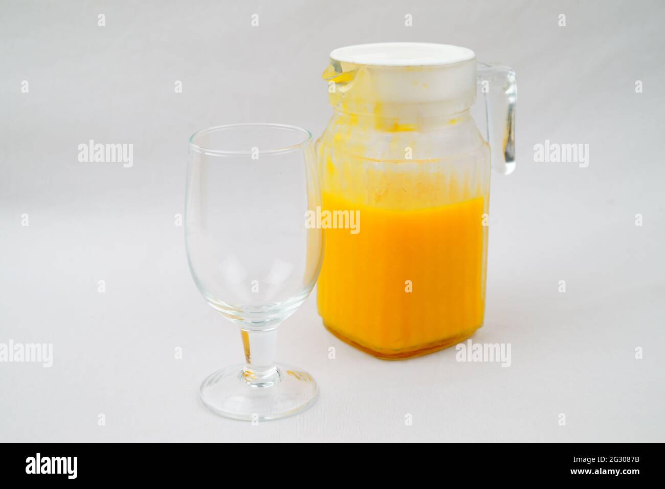 Una foto ad alto angolo di una caraffa di succo di mango fresco su uno sfondo bianco Foto Stock