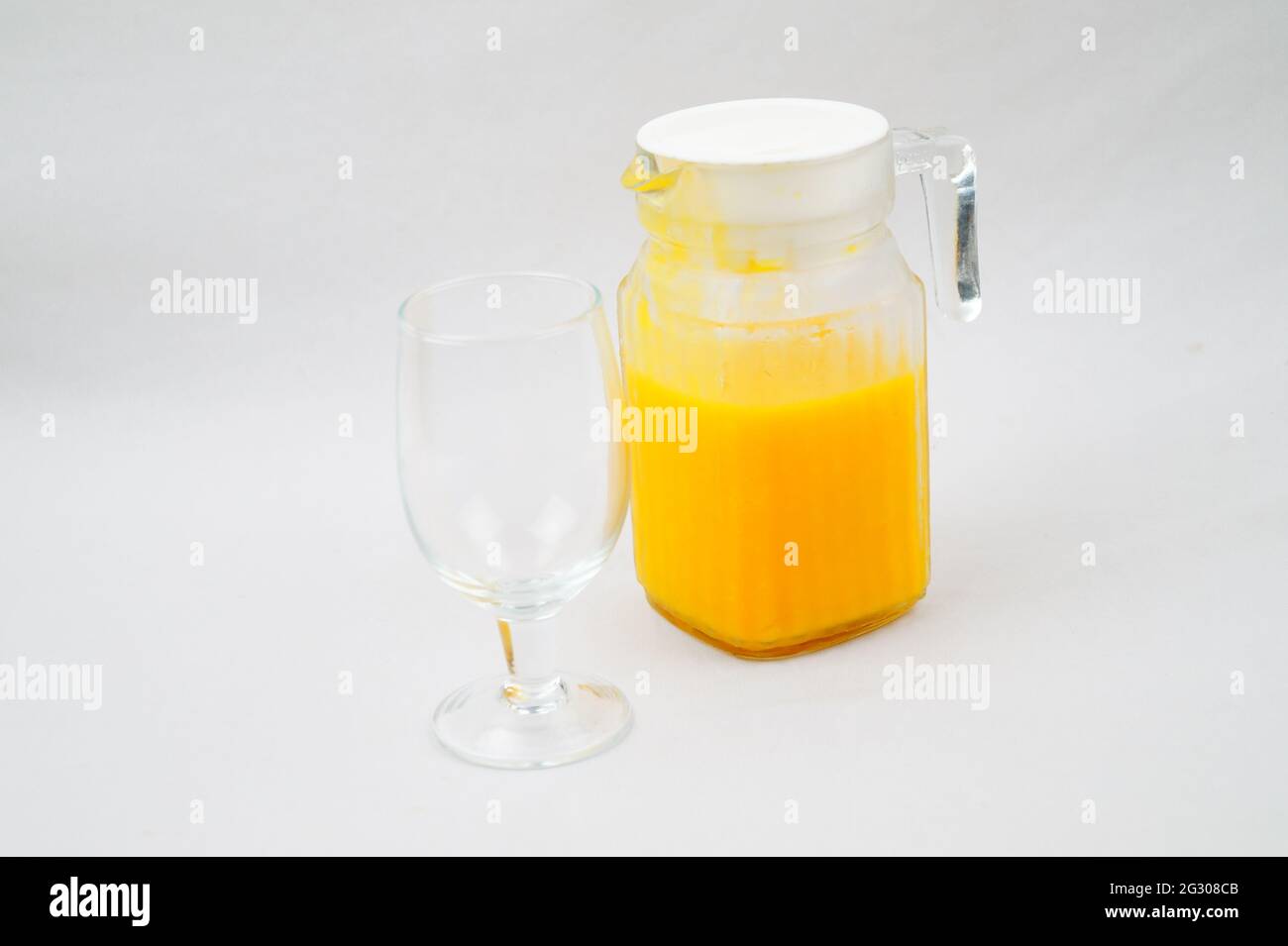 Una foto ad alto angolo di una caraffa di succo di mango fresco su uno sfondo bianco Foto Stock