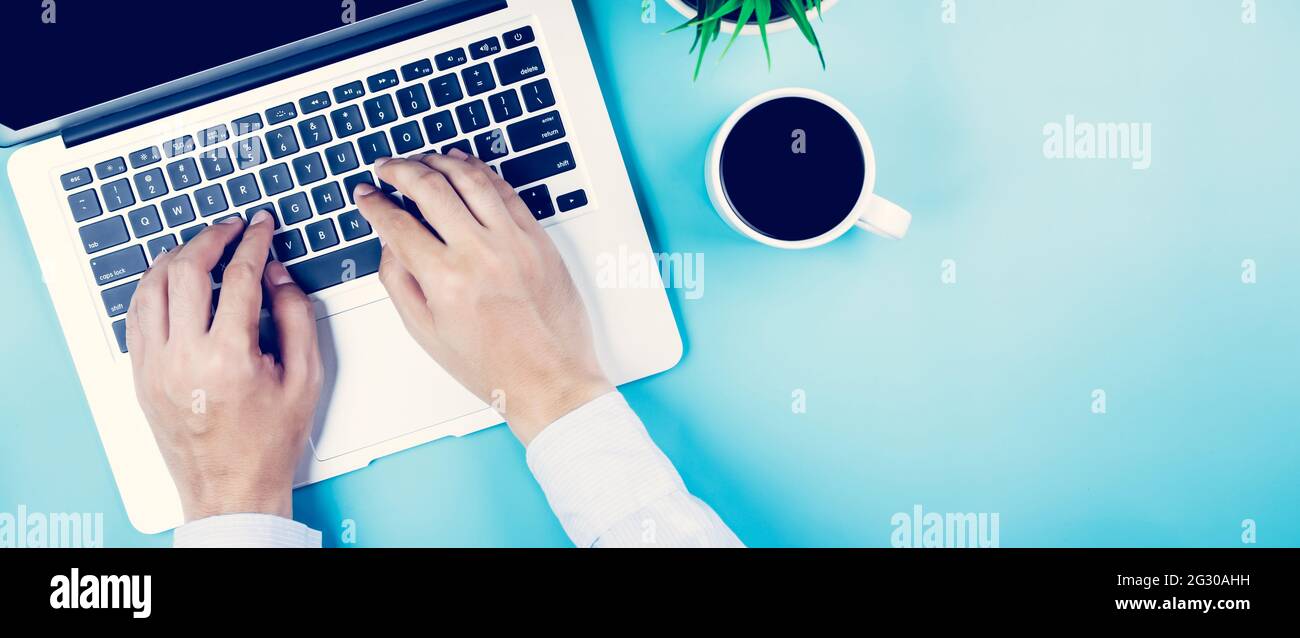 Posa piatta, mano di uomo d'affari che lavora su computer portatile con pianta e tazza di caffè sulla scrivania in ufficio, sul posto di lavoro e notebook e vaso albero, opere Foto Stock