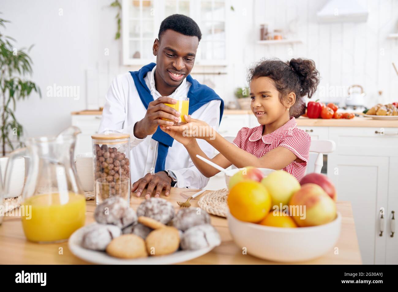 Il padre e il bambino beve succo di frutta fresco a colazione Foto Stock