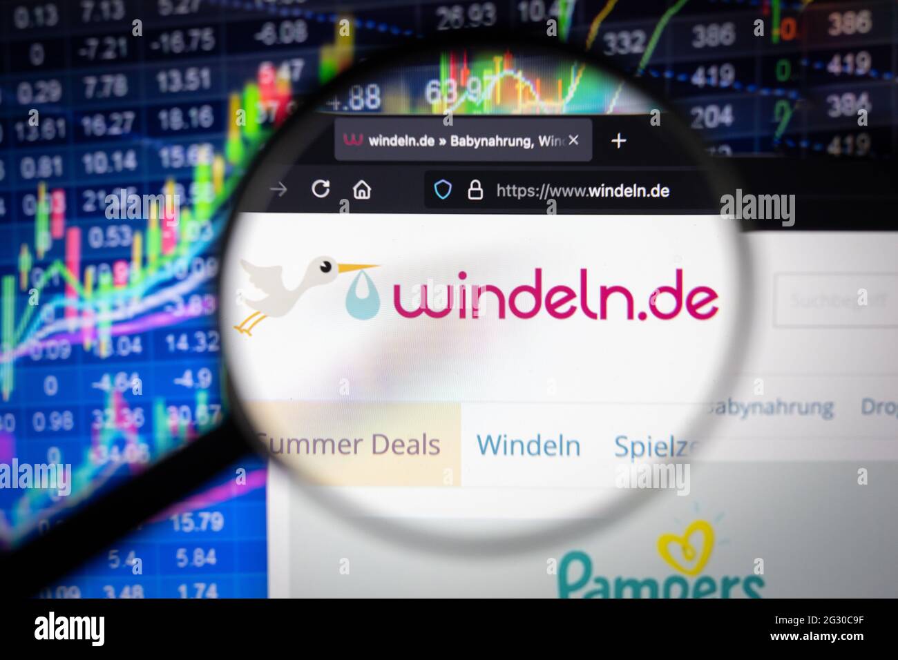Windeln.de logo aziendale su un sito Web con sviluppi sfocati del mercato azionario sullo sfondo, visto su uno schermo del computer attraverso una lente di ingrandimento Foto Stock