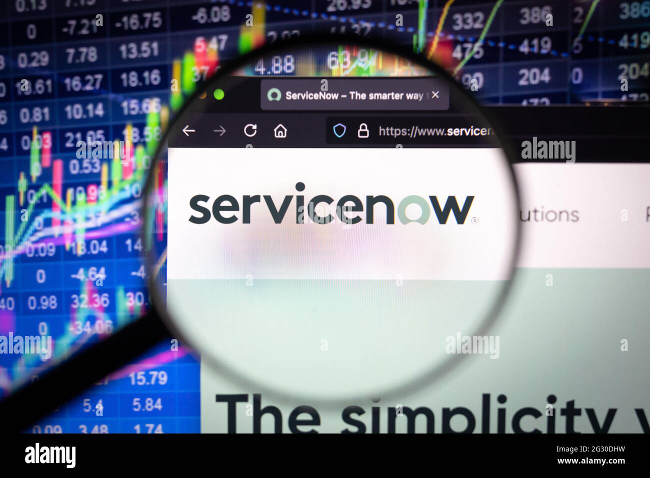 Logo di Servicenow Company su un sito web con sviluppi del mercato azionario sfocato in background, visto su uno schermo del computer attraverso una lente di ingrandimento Foto Stock