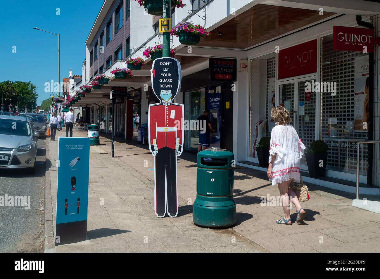 Ascot, Berkshire, Regno Unito. 13 giugno 2021. La gente cammina oltre non lasciare la vostra guardia giù le indicazioni in Ascot High Street. Il numero di risultati positivi di Covid-19 nel Berkshire è in aumento su un tasso giornaliero come la variante indiana di Covid-19 sweep in tutto il Regno Unito. Boris Johnson dovrebbe annunciare domani che la revoca delle restrizioni di blocco di Covid-19 deve essere messa in attesa per un altro mese. Credito: Maureen McLean/Alamy Foto Stock