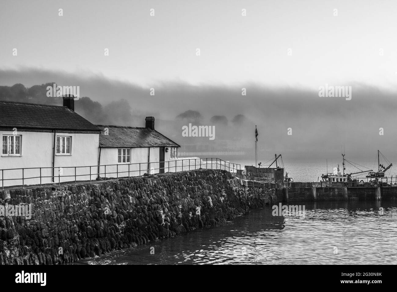 Immagine in bianco e nero scattata all'alba, al porto di Cobb, a Lyme Regis in Dorset. Scena della donna tenente francese. Spazio di copia Foto Stock