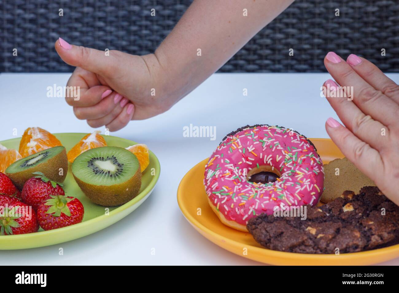 Sano e malsano, due piatti con frutta e biscotti, Thumbs up con frutta, concetto di cibo naturale Foto Stock