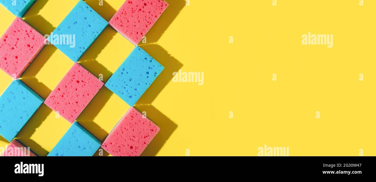 Spugne per la pulizia della casa su sfondo giallo, spazio per la copia. Disposizione piatta o vista dall'alto. Servizio di pulizia o di pulizia con spazio. Ombre dure alla luce del sole. Banner orizzontale lungo Foto Stock