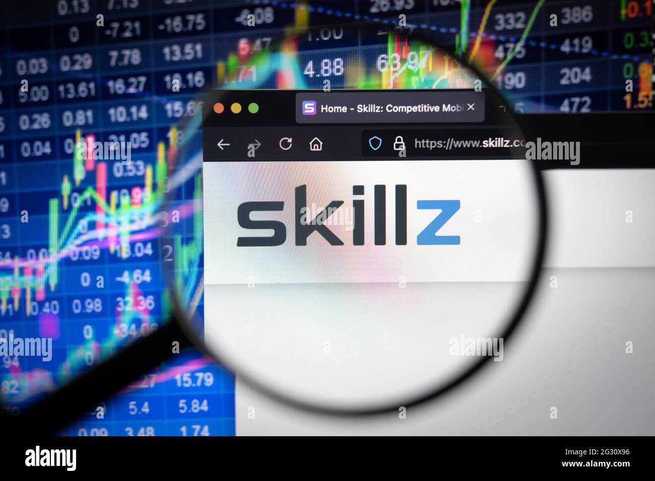 Logo della società Skillz su un sito web con sviluppi sfocati del mercato azionario in background, visto su uno schermo del computer attraverso una lente di ingrandimento Foto Stock