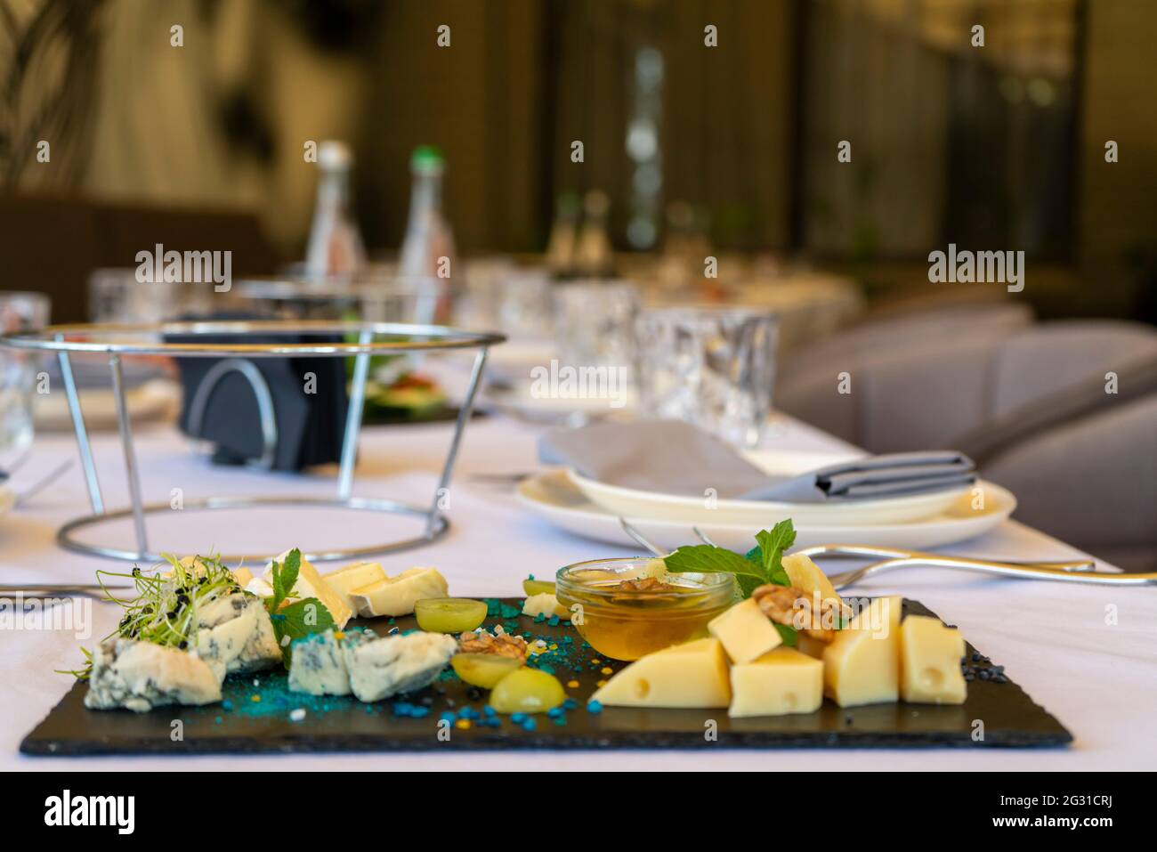 Spuntini assortiti su un piatto di pietra nera su un tavolo del ristorante su uno sfondo della finestra Foto Stock