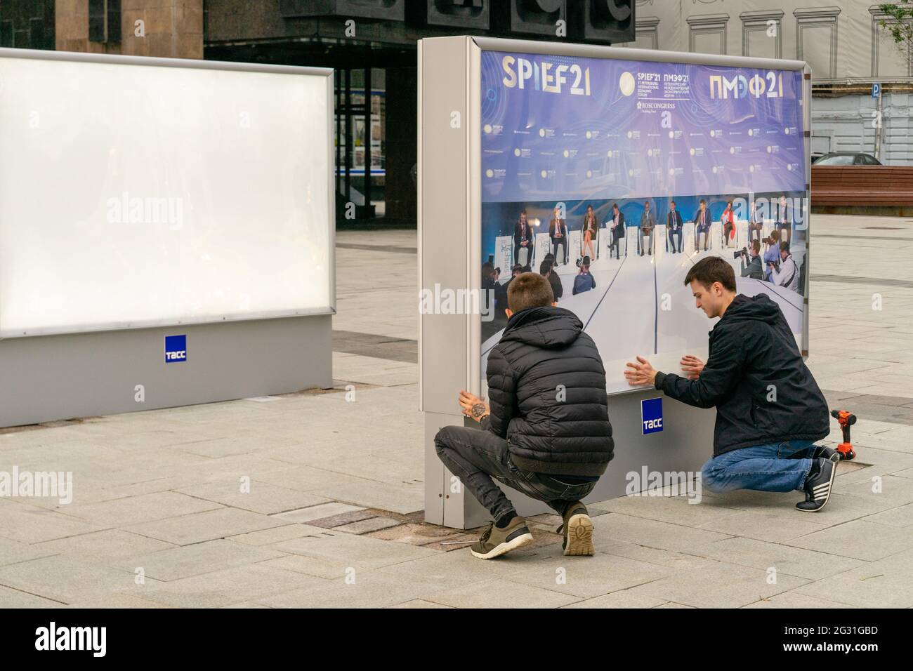 Due lavoratori maschili hanno allestito mostre espositive all'aperto con immagini dell'agenzia Tass da SPIEF, Tverskoy blvd, Mosca, Russia Foto Stock