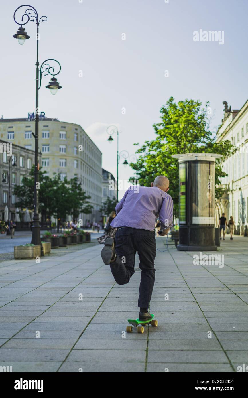 uomo in abbigliamento da lavoro a bordo di uno skateboard per le strade della città Foto Stock