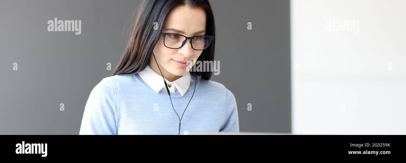 Giovane donna in cuffia che guarda lo schermo del computer portatile Foto Stock