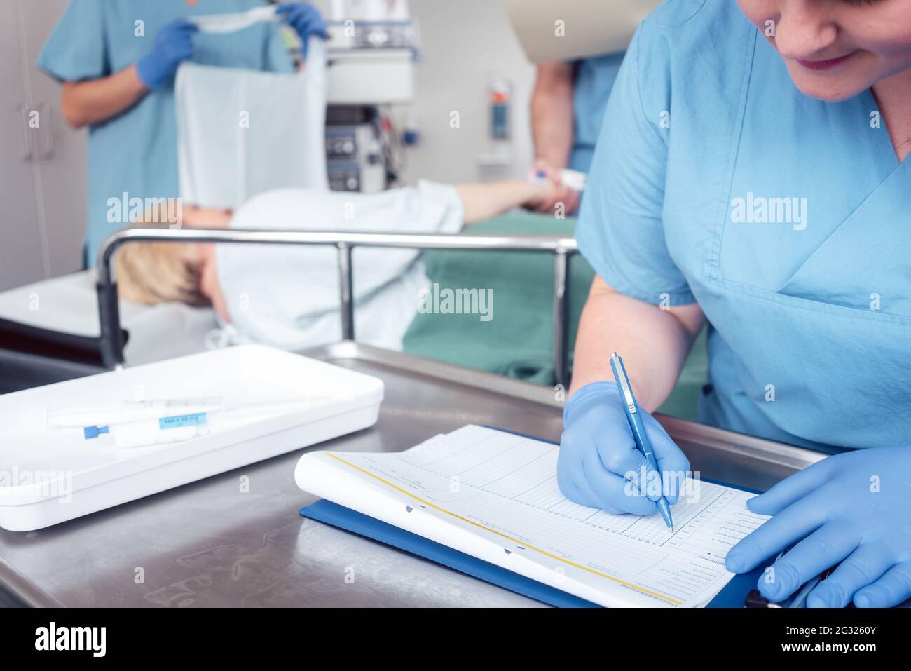 Nurse che scrive il rapporto di pre-chirurgia su file Foto Stock