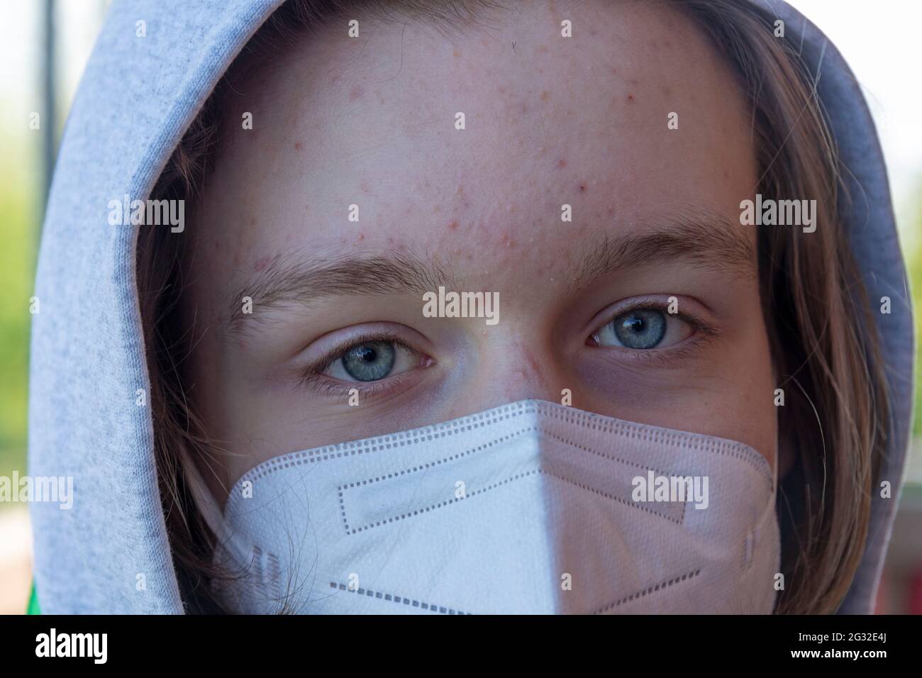 Ragazzo adolescente che indossa cappuccio e maschera facciale, Germania Foto Stock